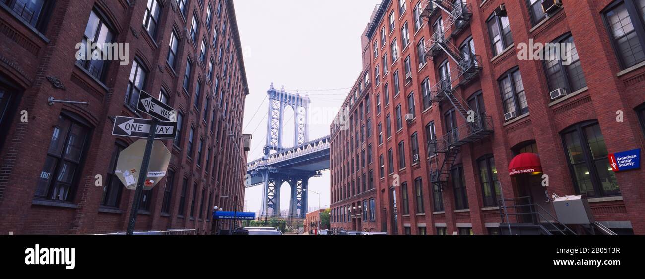 Low angle view of a suspension bridge viewed through buildings, Manhattan Bridge, Brooklyn, New York City, New York State, USA Stock Photo