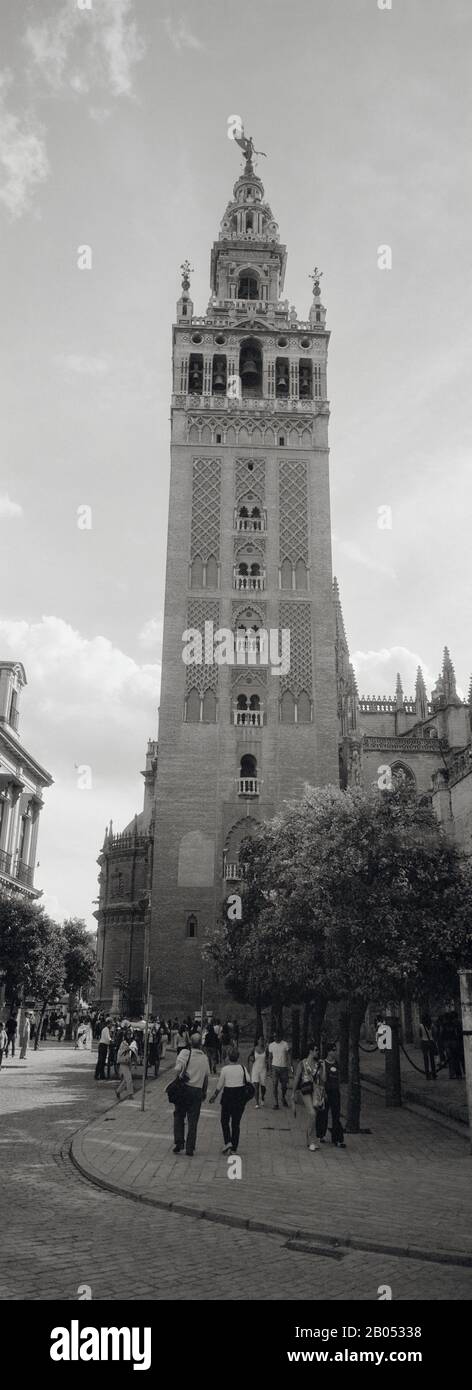 Group of people walking near a church, La Giralda, Seville Cathedral, Seville, Seville Province, Andalusia, Spain Stock Photo