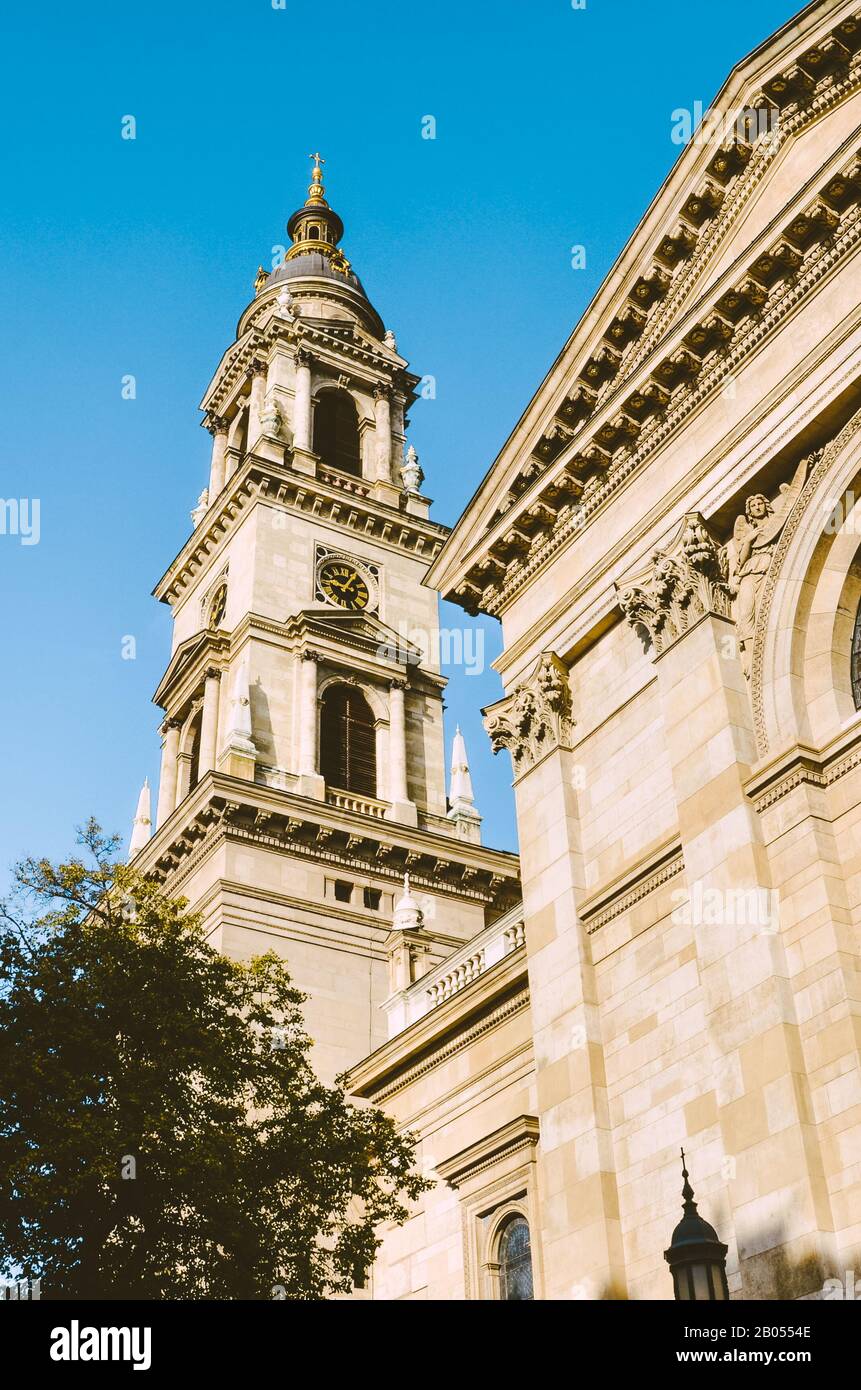 Tower of St. Stephen's Basilica in Budapest, Hungary with blue sky above. Historical sample of neoclassical architecture. Tourist landmark in the center of the Hungarian capital city. Vertical photo. Stock Photo