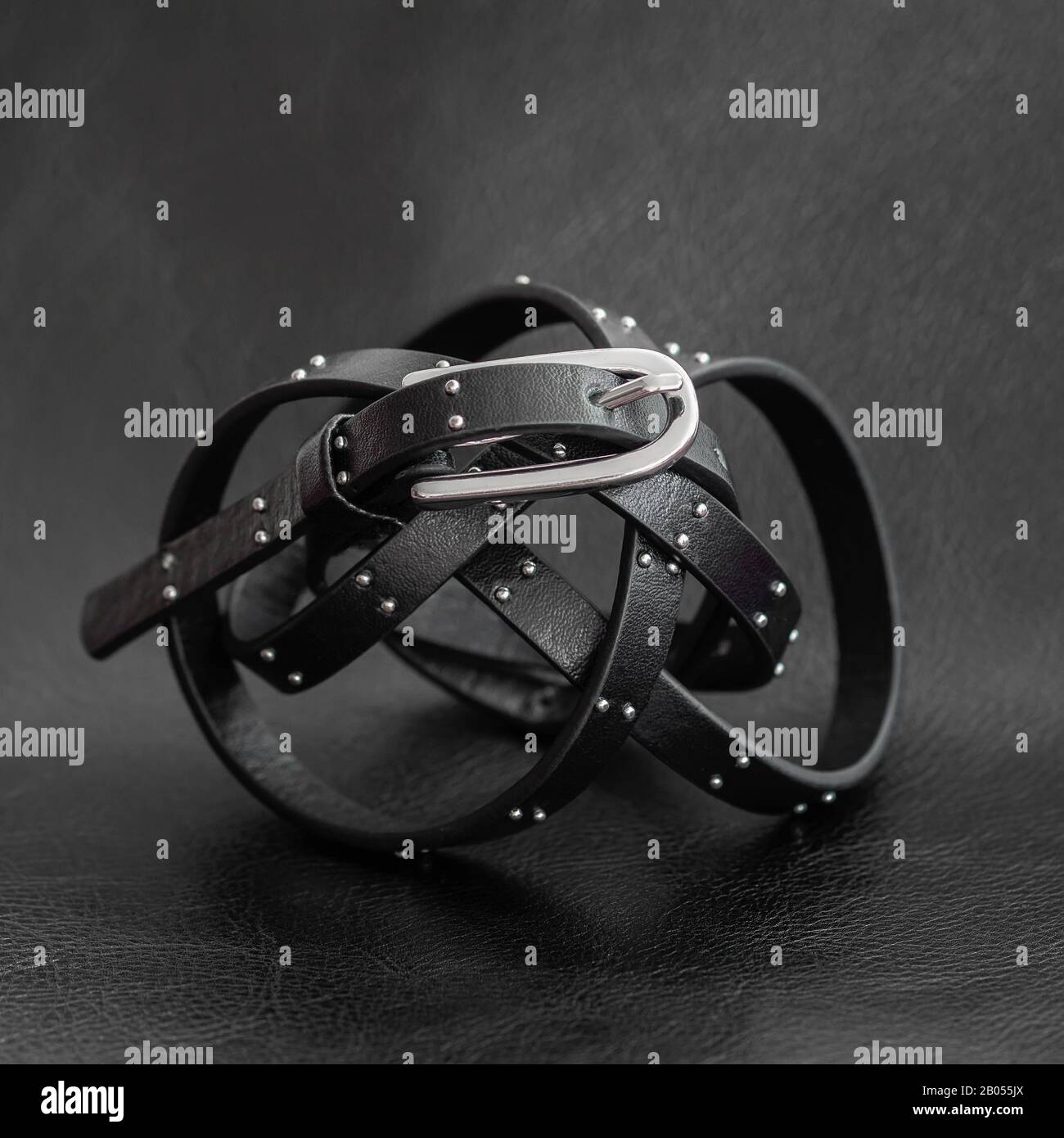 thin-black-rolled-belt-with-silver-metal-fittings-on-a-dark-background