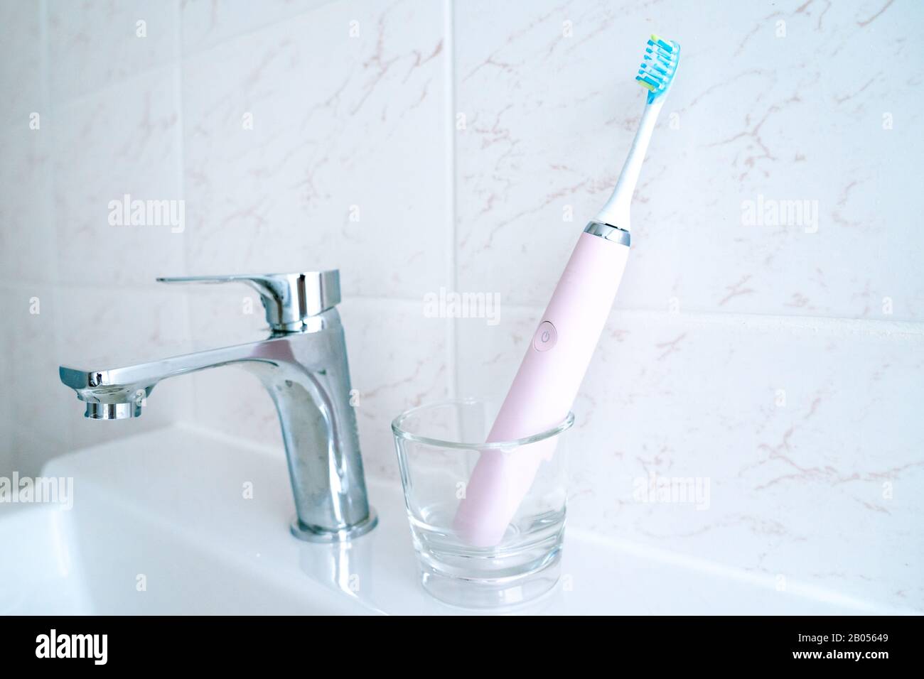 Pink electric toothbrushes and glass in the bathroom at home ...
