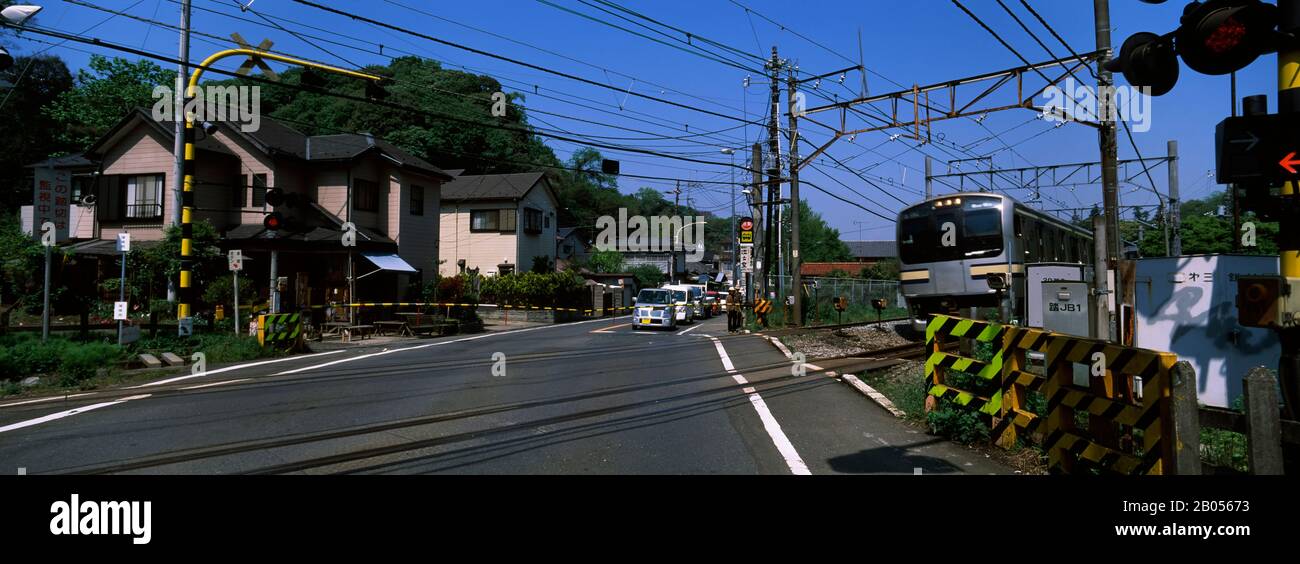 Cars waiting for passing train at a railroad crossing, Kamakura, Kanagawa Prefecture, Kanto Region, Japan Stock Photo