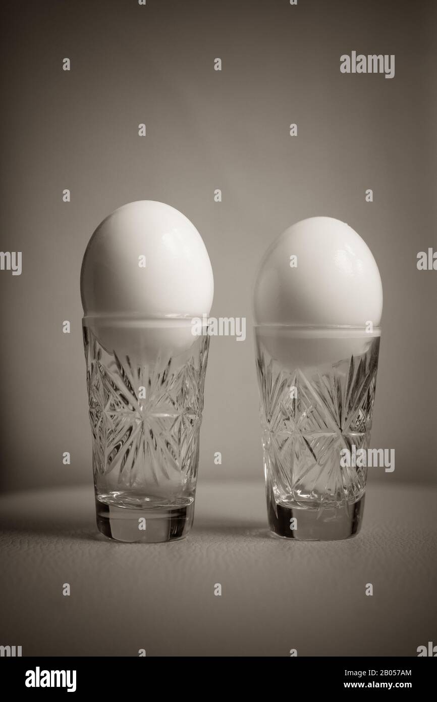 Two boiled chicken eggs peeled in a crystal glass on the table Stock Photo