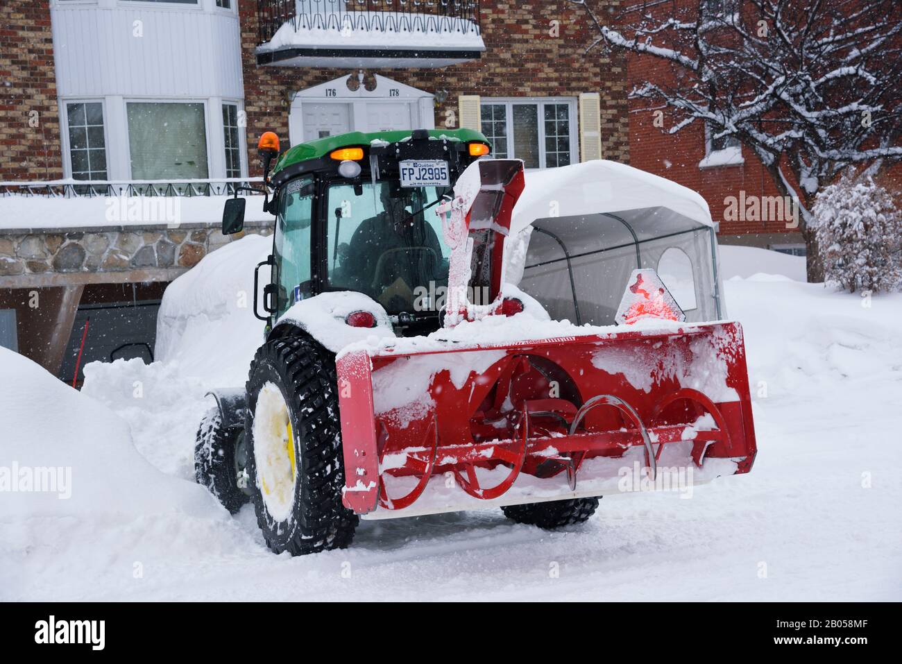 Snowblower tractor clearing snow in front of a house, Laval, province of Quebec, Canada. Stock Photo