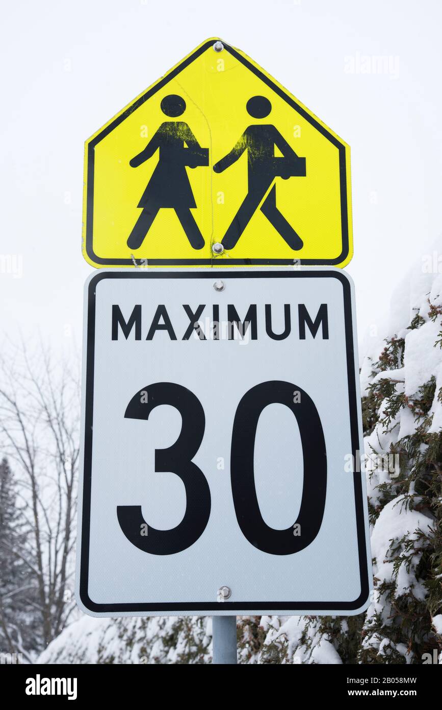 School children crossing and speed limit signs on a signpost, province of Quebec, Canada. Stock Photo