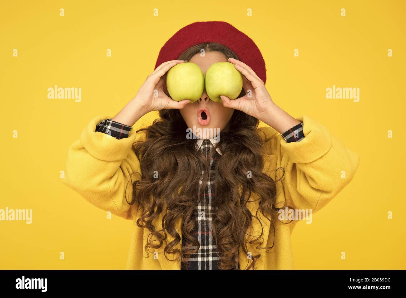 Impressing harvest. Girl cute long curly hair hold apples. Child girl emotional face expression. Delicious harvest. Harvest season. Child kid surprised face hold apples. Healthy food concept. Stock Photo