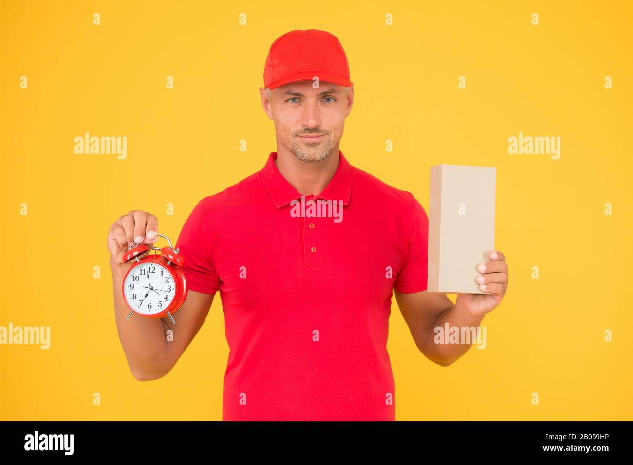 Take your shopping time. Delivery man hold clock and box yellow background. Online shopping. Cyber Monday. Sales shopping. Shopping and fast delivery. Time to shop, copy space. Stock Photo