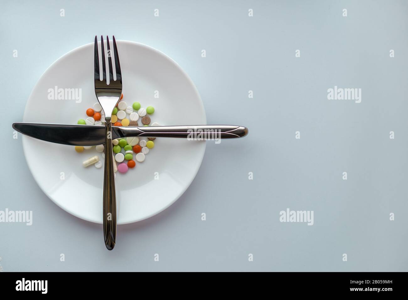 Pills on a white plate. Gesture with a knife and fork looking forward ...