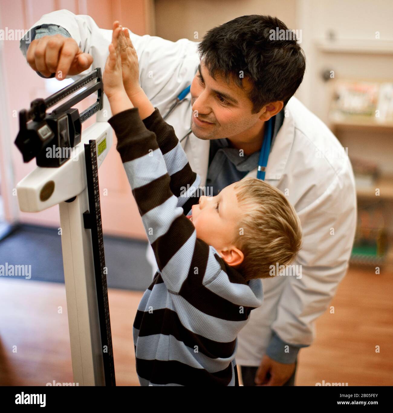 Doctor measuring young patient's weight on medical scales Stock Photo