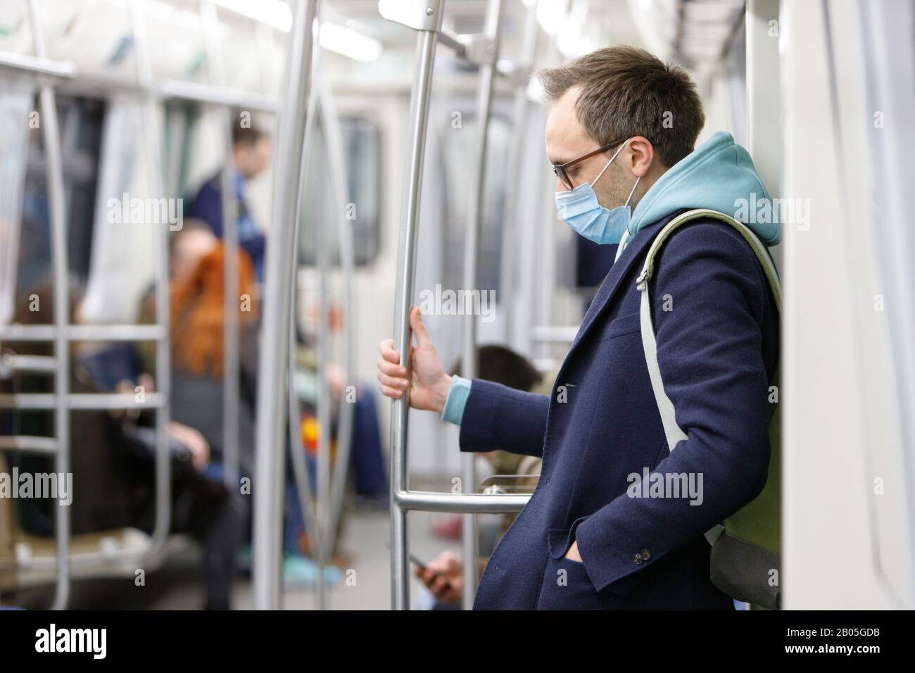 Exhausted man in eyeglasses feeling sick, wearing protective mask against transmissible infectious diseases and as protection against coronavirus Stock Photo