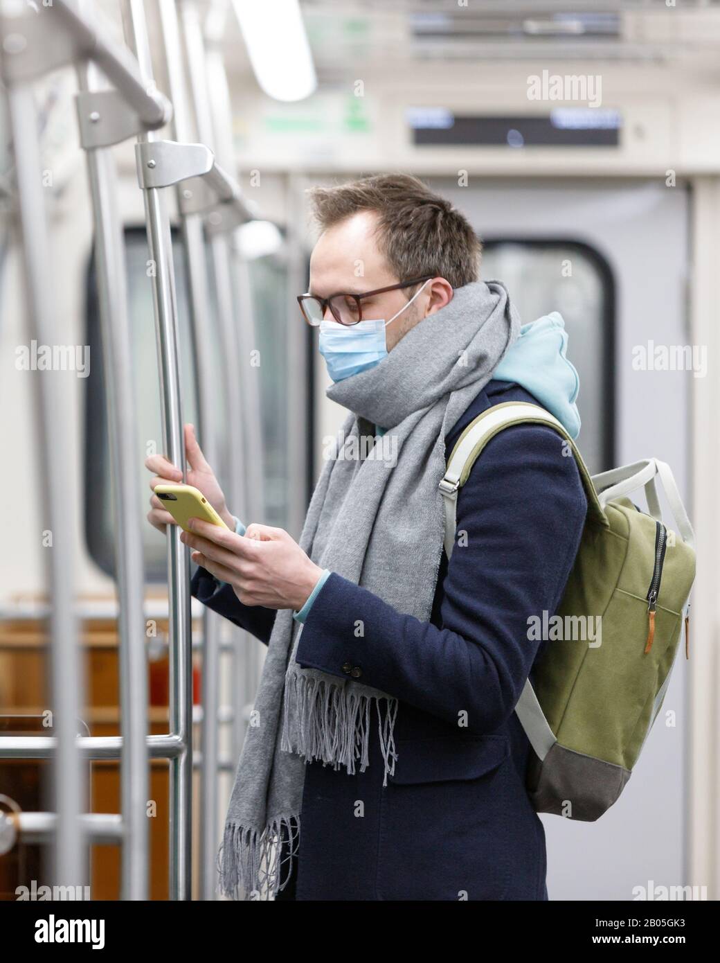 Ill man in glasses feeling sick, wearing protective mask against transmissible infectious diseases and as protection against the flu in transportation Stock Photo