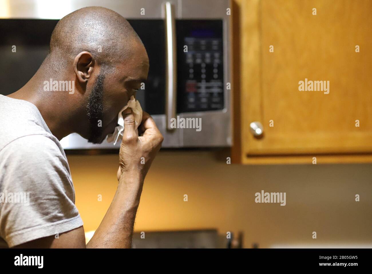 African-American man blowing his nose, while sick with a cold or flu Stock Photo