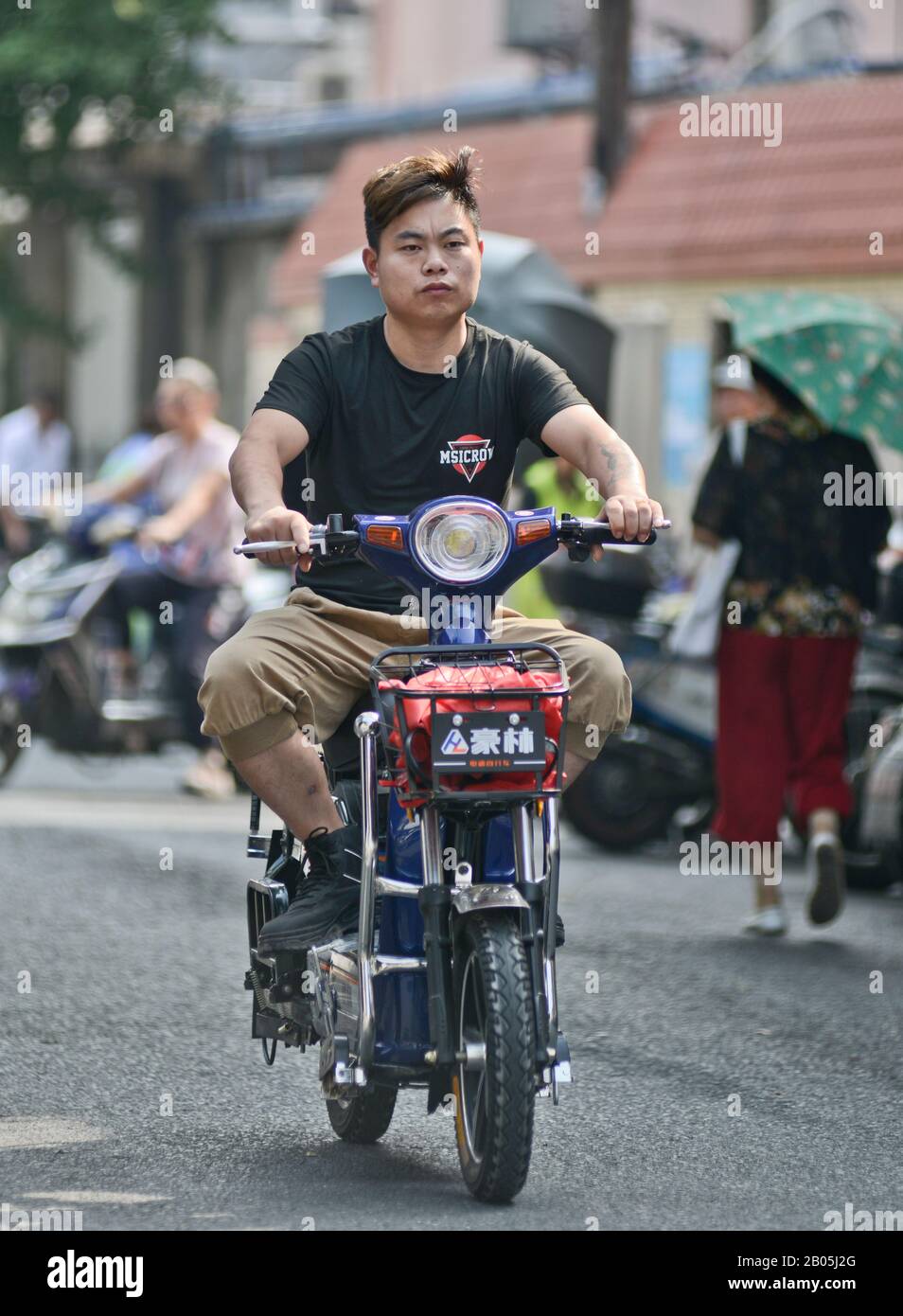 A chinese young man riding a scooter motorcycle in Shanghai Old Town, Penglai Road, Huangpu. China Stock Photo