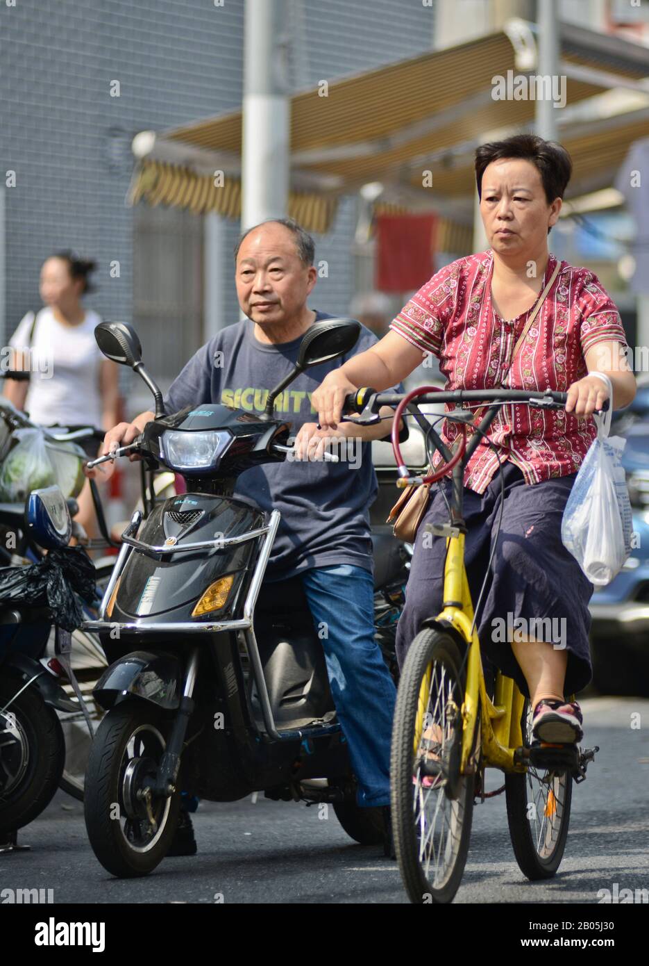 Chinese people on scooters and bicycles in Shanghai Old Town, Penglai Road, Huangpu. China Stock Photo