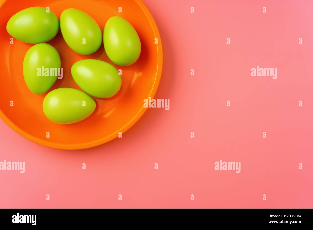 Close up of green Easter eggs in a bright plate on vibrang orange and red background Stock Photo