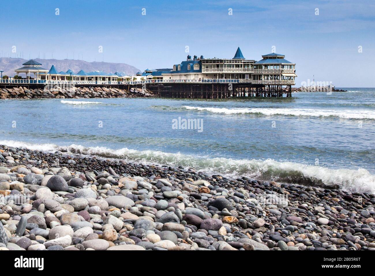 The pier and well known ' La Rosa Nautica' restaurant are seen from the pebble beach. Stock Photo