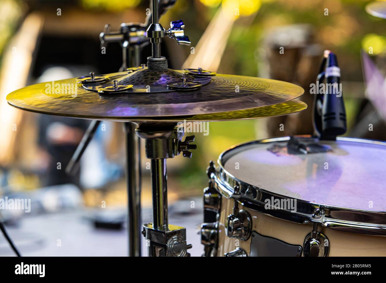 A close up shot of a hi hat cymbal on a drum set, with green bokeh and