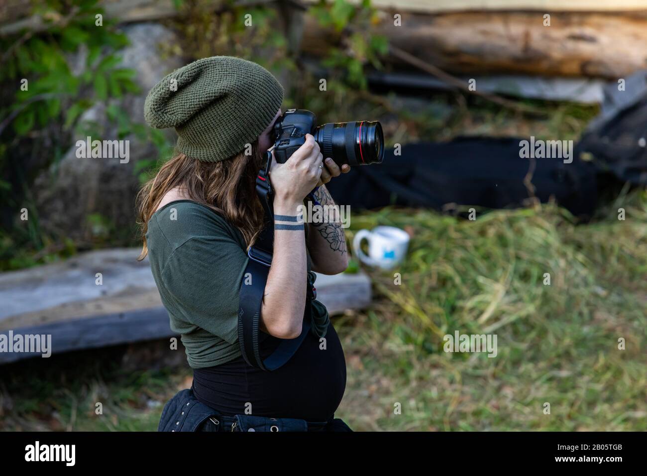 rig Sammenbrud pegs A high angle and side profile view of a professional female photographer,  with tattooed arms and wearing a green beanie hat, taking photos in nature  Stock Photo - Alamy