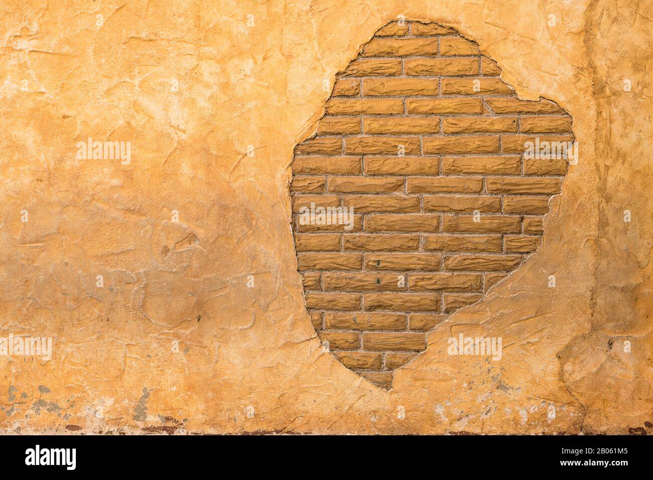 Brick behind Lathe Stucco Wall in Brown and Beige colors from Old Building Stock Photo