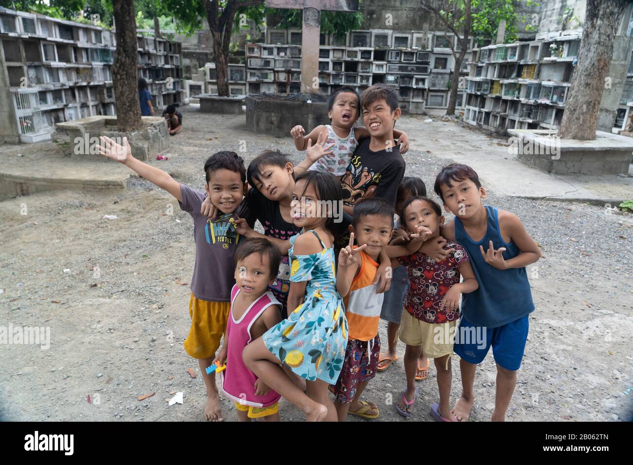 A group of young Filipino children who live within the grounds of  a cemetery pose for the camera. Stock Photo