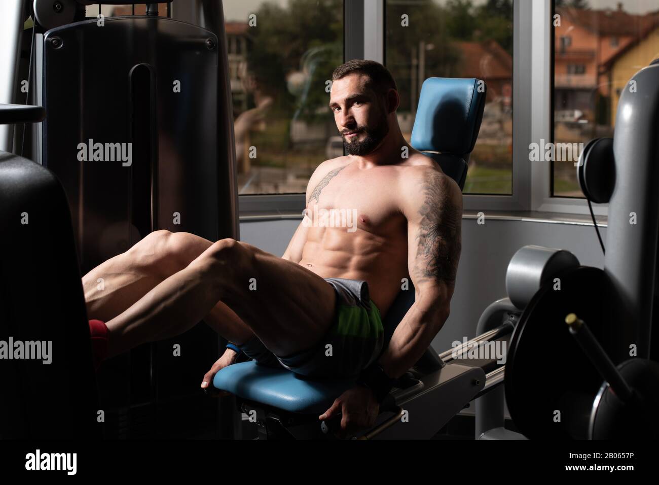 Strong Man In The Gym And Exercising Quadriceps And Glutes On Machine