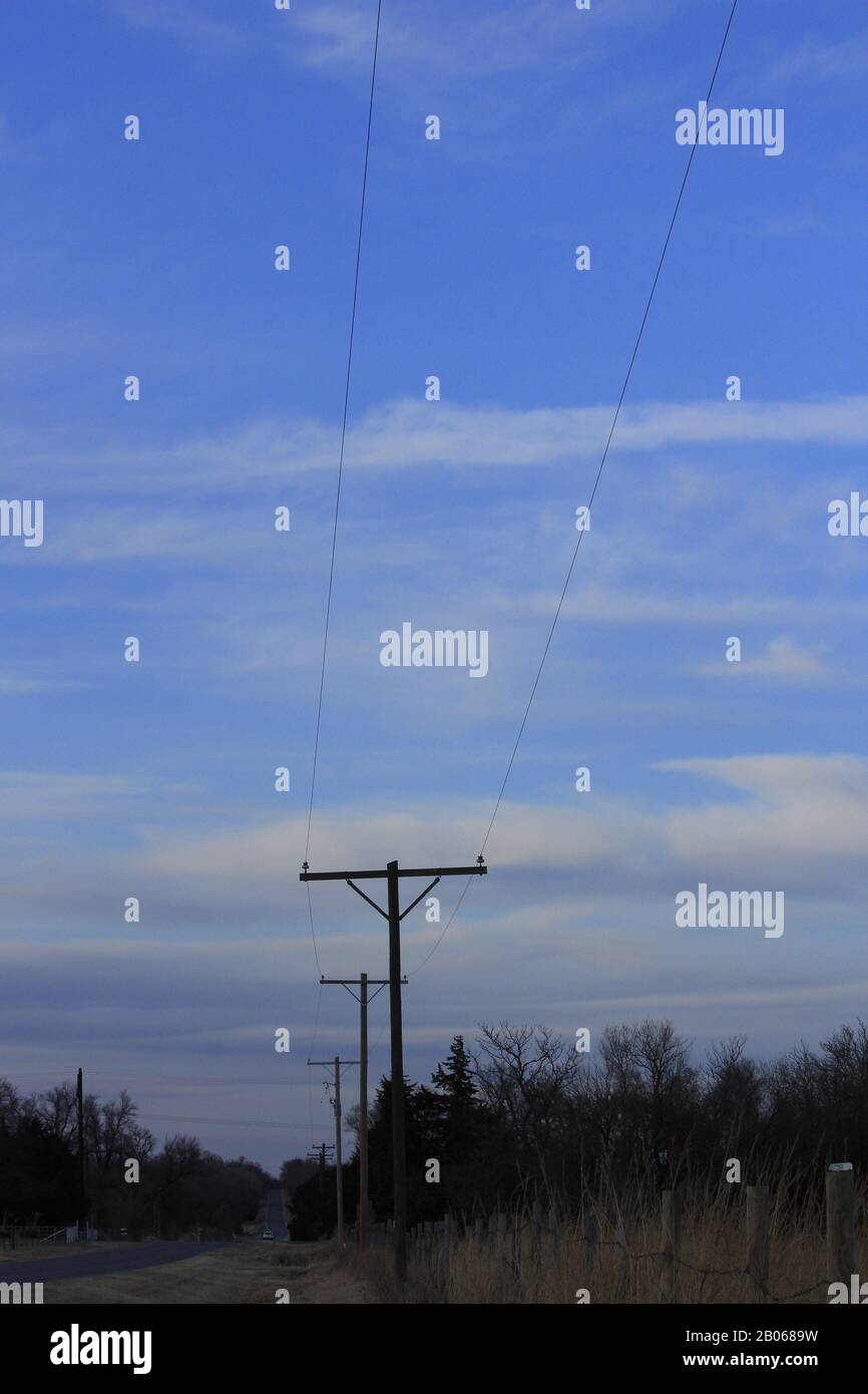 Power lines out in the country with blue sky and tree's in Kansas. Stock Photo