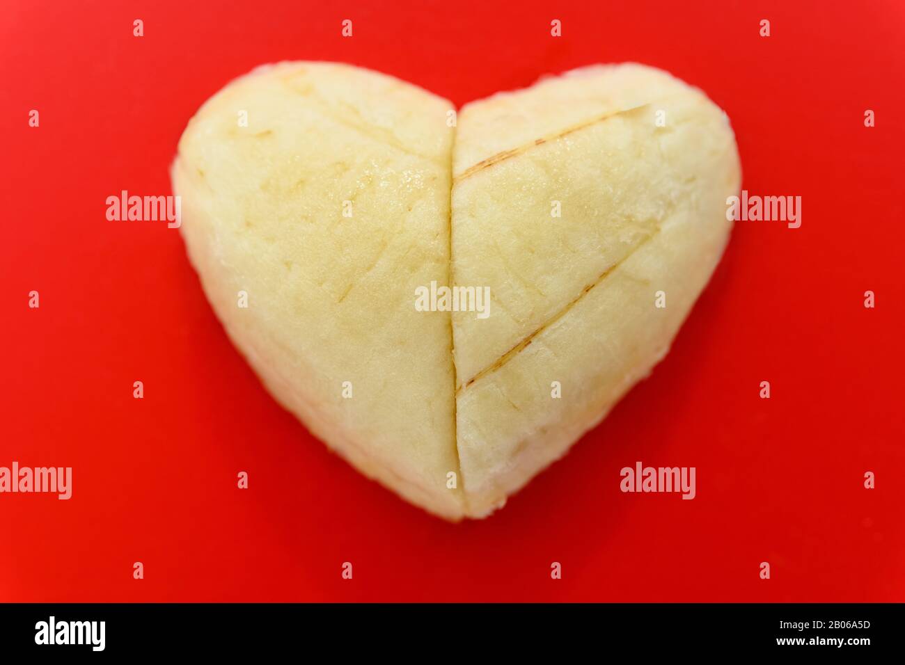 two slices of banana shaped as a heart on red background Stock Photo