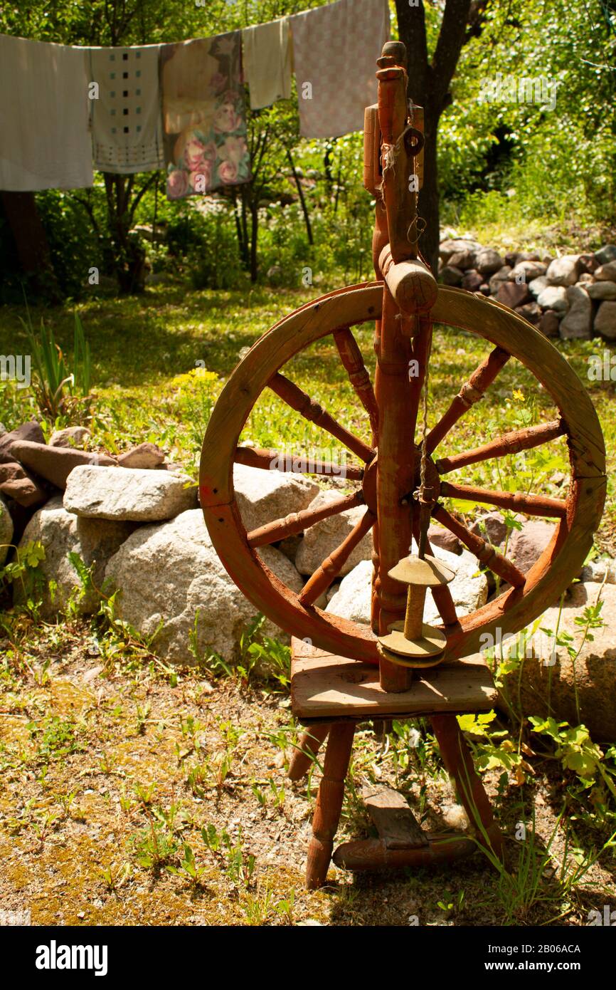 Ancient wooden spinning wheel with wheel and spindle in the garden on