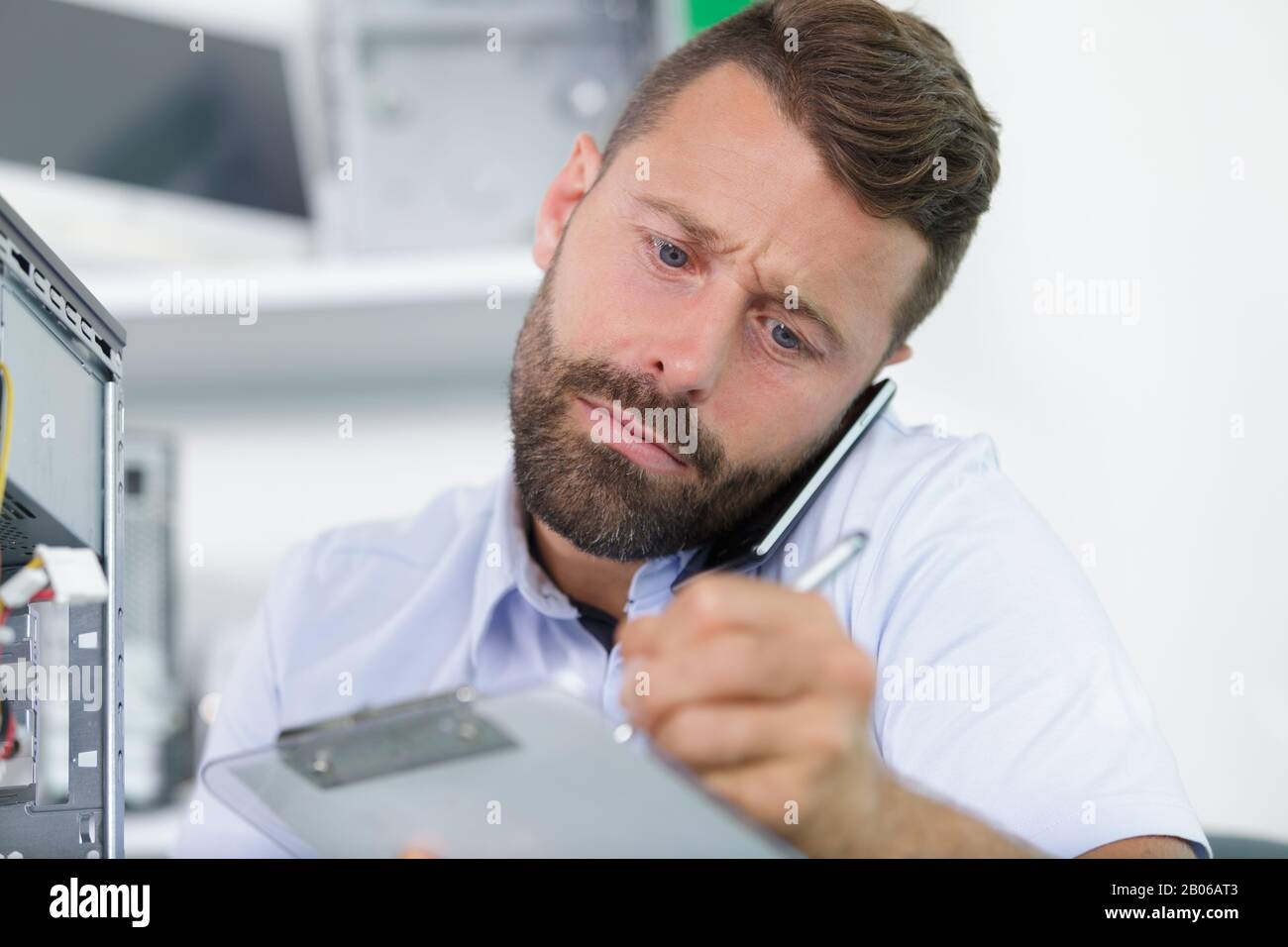 man on the phone writing on clipboard Stock Photo