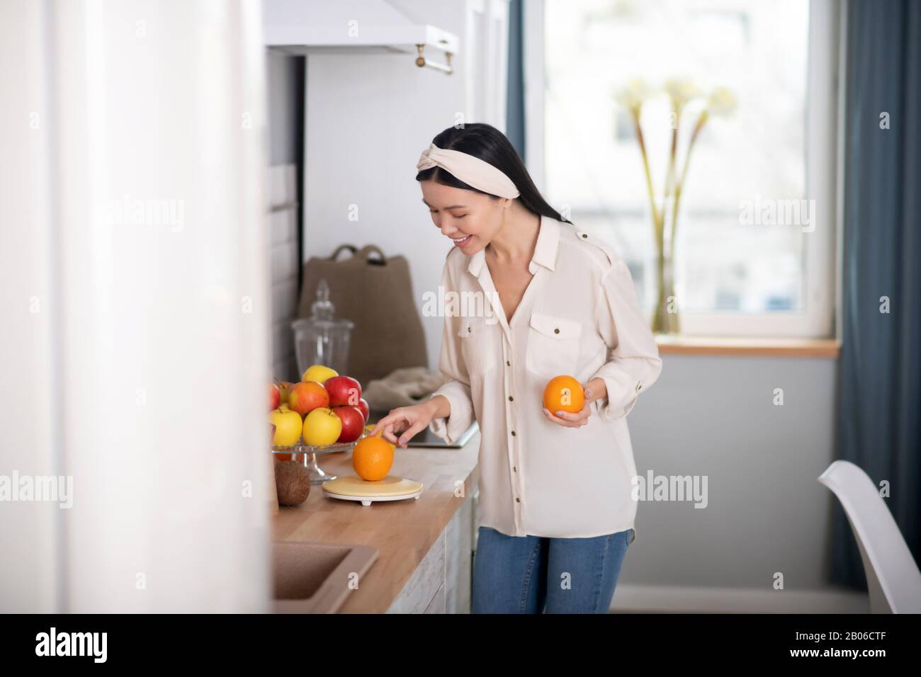 Young girl standing holding an orange in her hand Stock Photo - Alamy