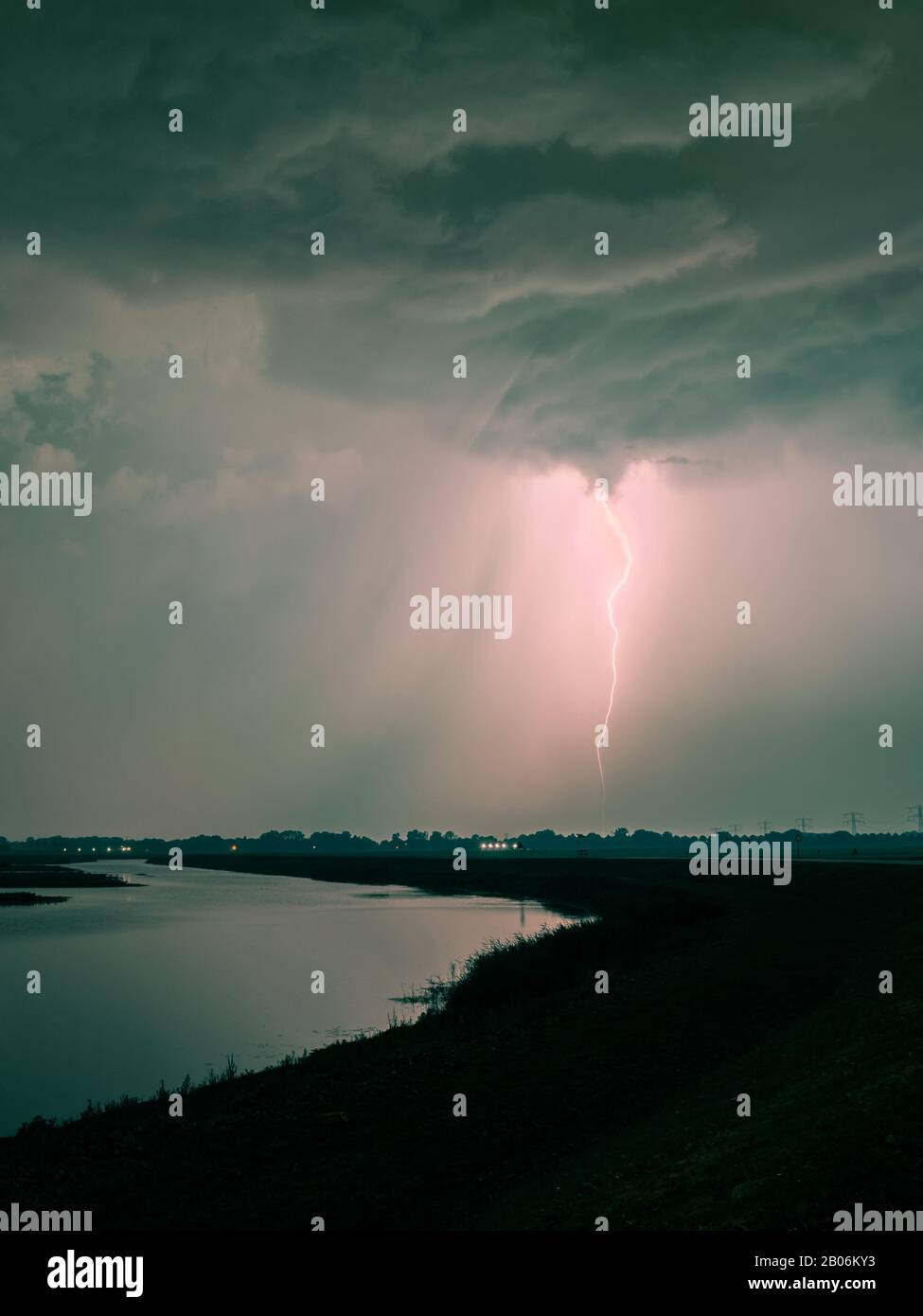 Angry sky over a river with lightning bolt striking down to earth Stock Photo