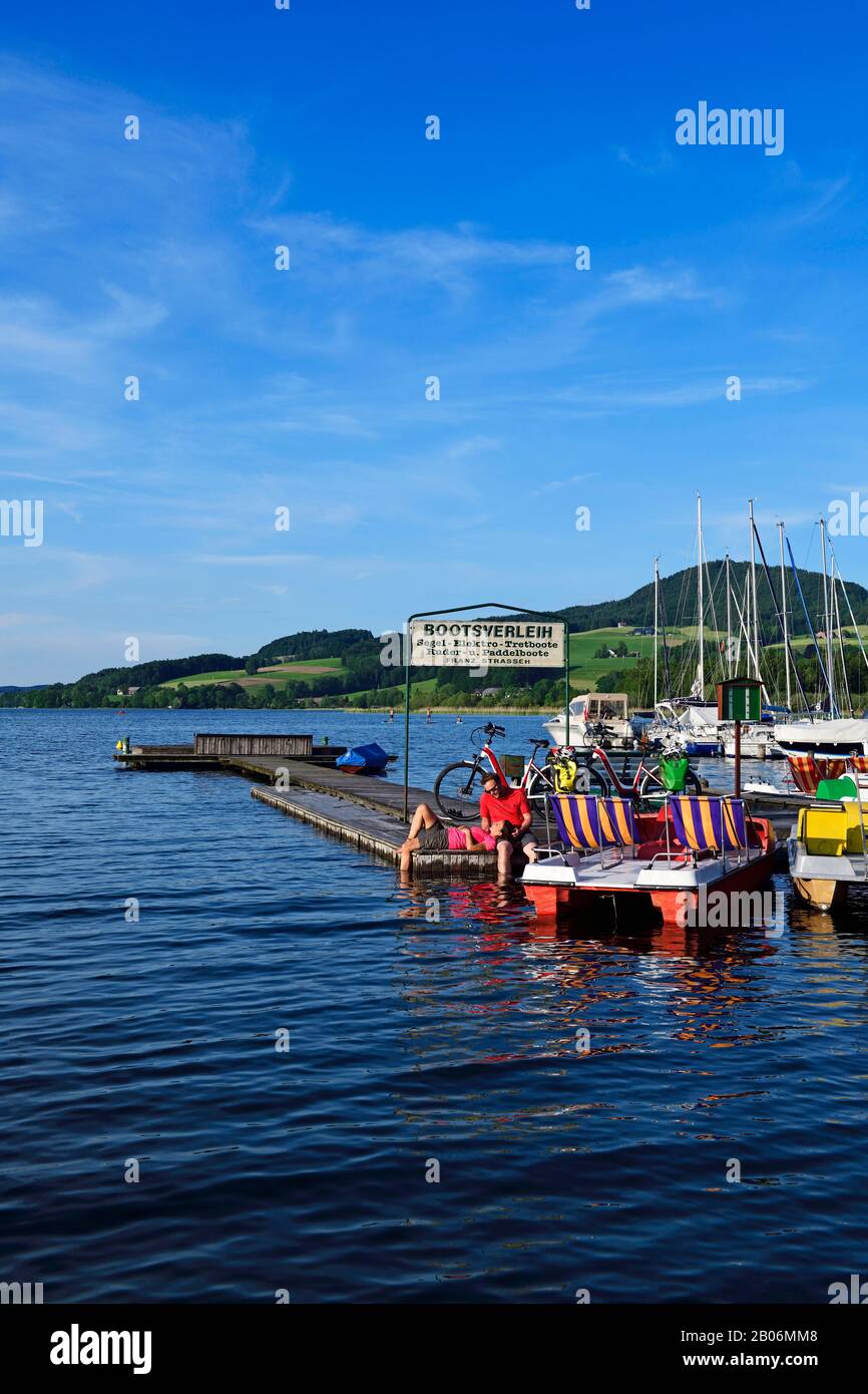 Couple with electric bikes pauses on a landing stage at Lake Obertrumer See, Obertrum, Salzburger Seenland, Salzburger Land, Austria Stock Photo