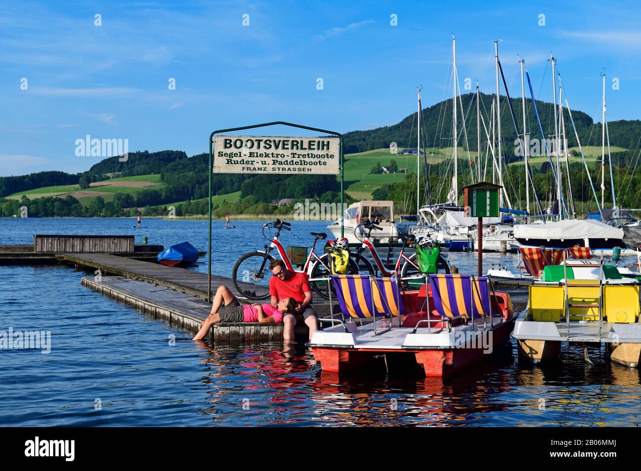 Couple with electric bikes pauses on a landing stage at Lake Obertrumer See, Obertrum, Salzburger Seenland, Salzburger Land, Austria Stock Photo