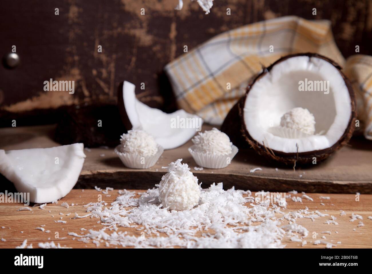 Close up of coconut with white pulp, coconut chip and sweet chocolate coconut truffles. Coconut shell, coconut flakes, small pieces of crashed nut, co Stock Photo