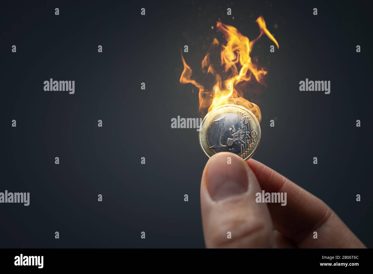 Hand with burning Euro coin Stock Photo