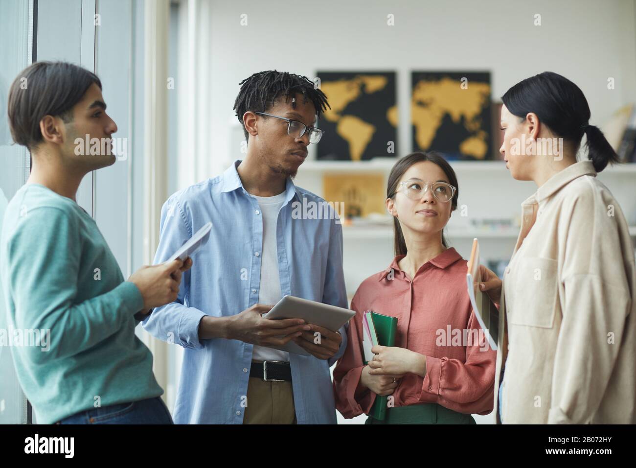 Multiethnic young people standing and talking to each other at office Stock Photo