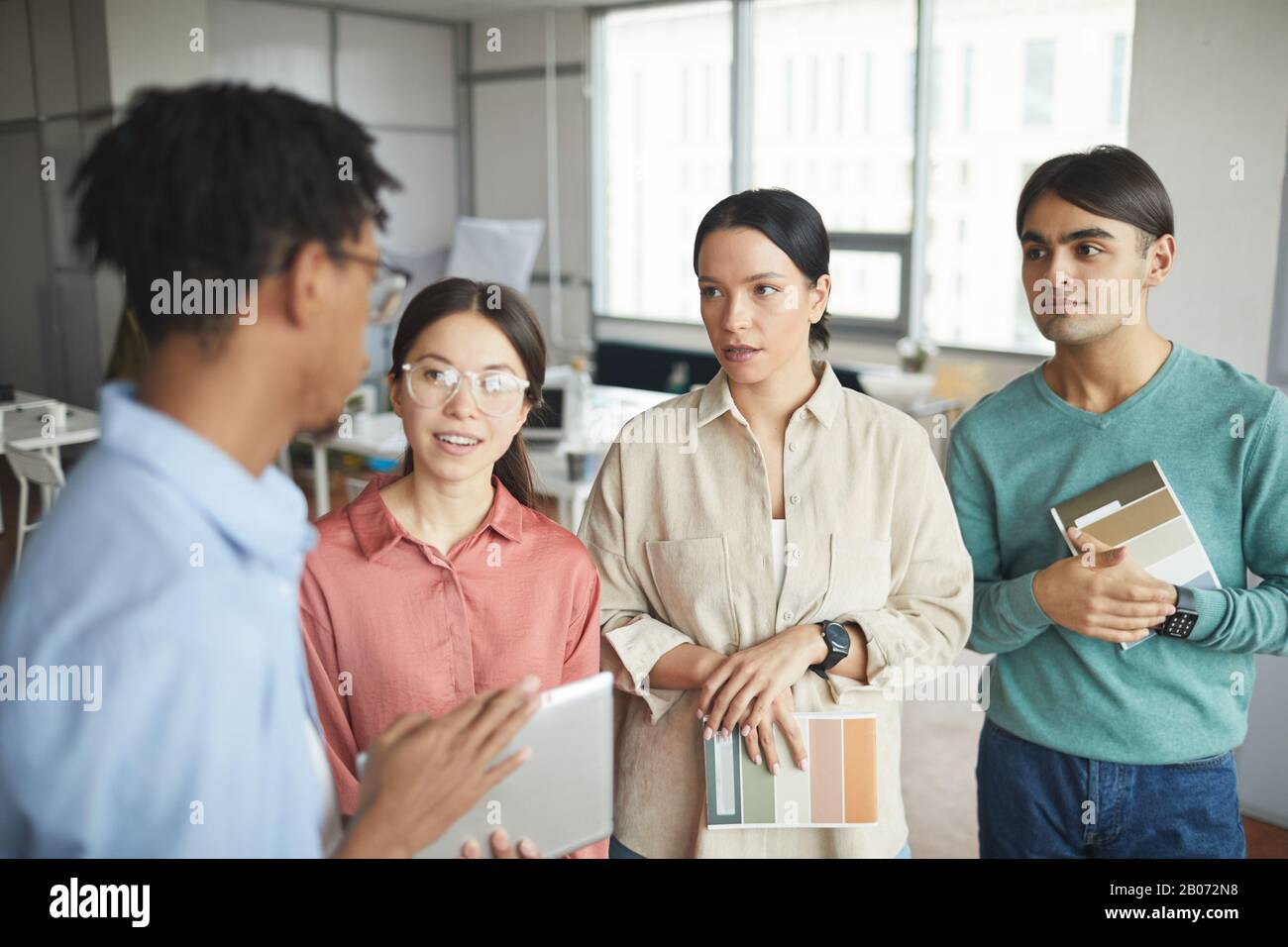 Young business people standing and listening to their leader before meeting at office Stock Photo