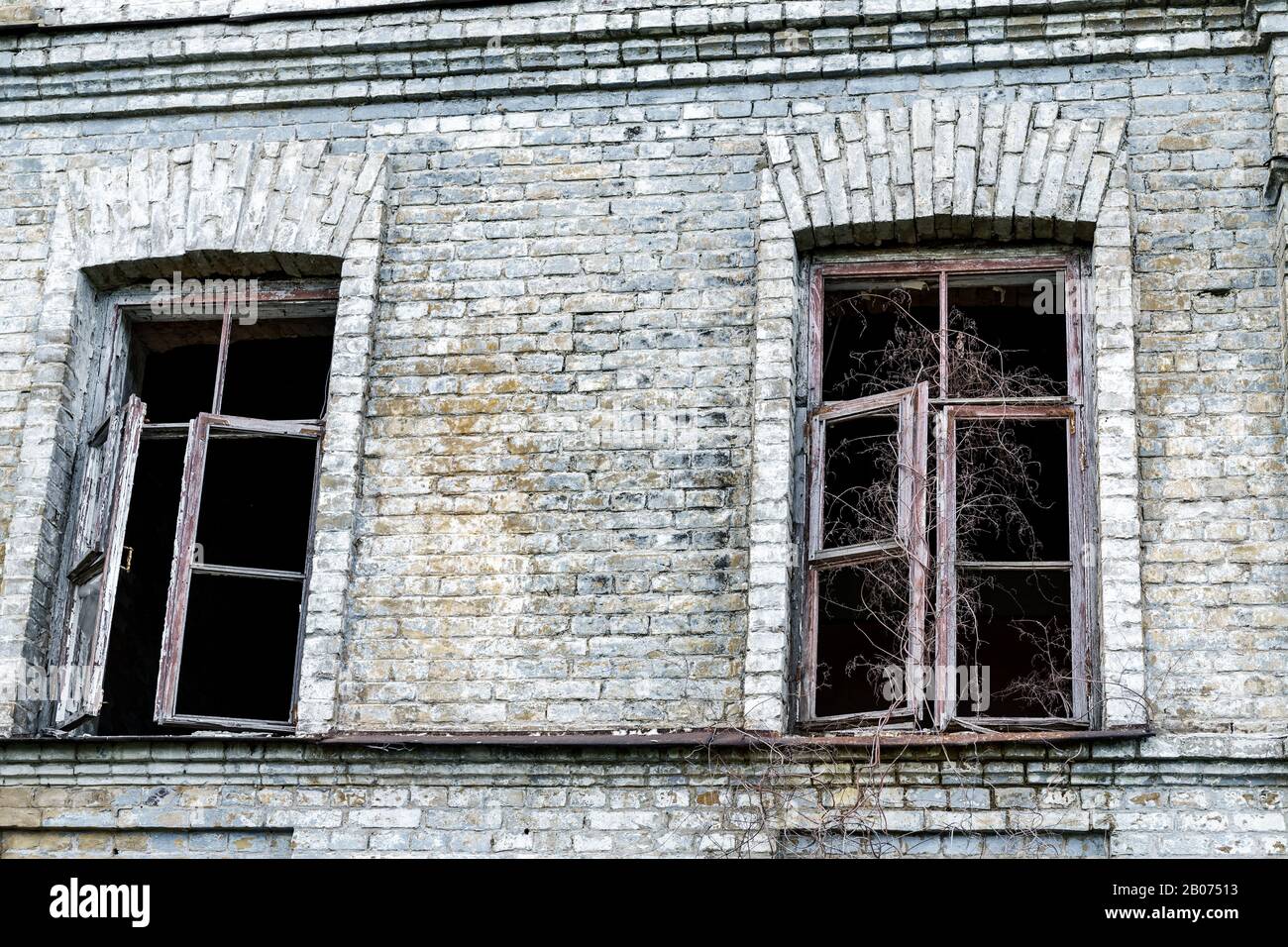 Old shabby ruined abandoned brick building wall facade with two wooden ...