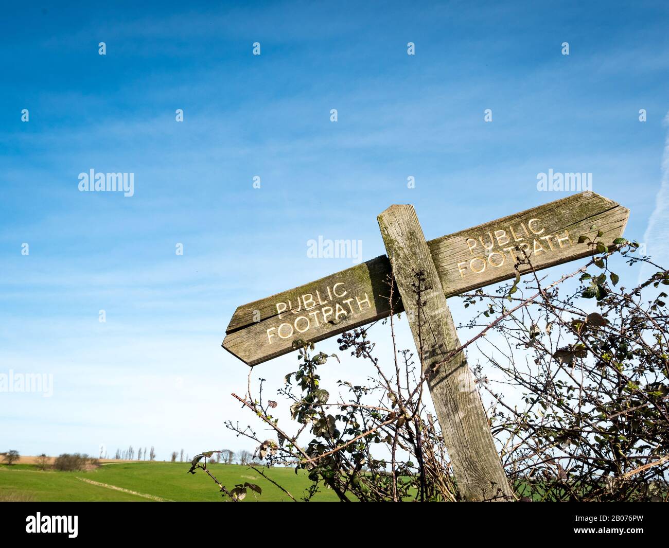 English countryside public footpath sign. A crooked sign covered in moss and lichen directing hikers on their route. Stock Photo