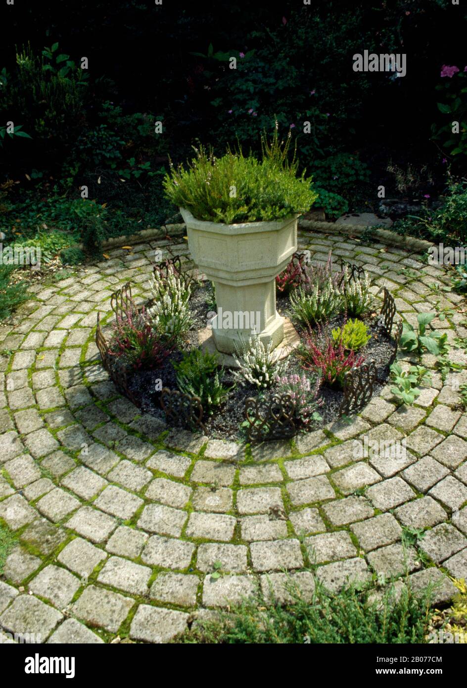 Round stone trough surrounded by circular laid path Stock Photo