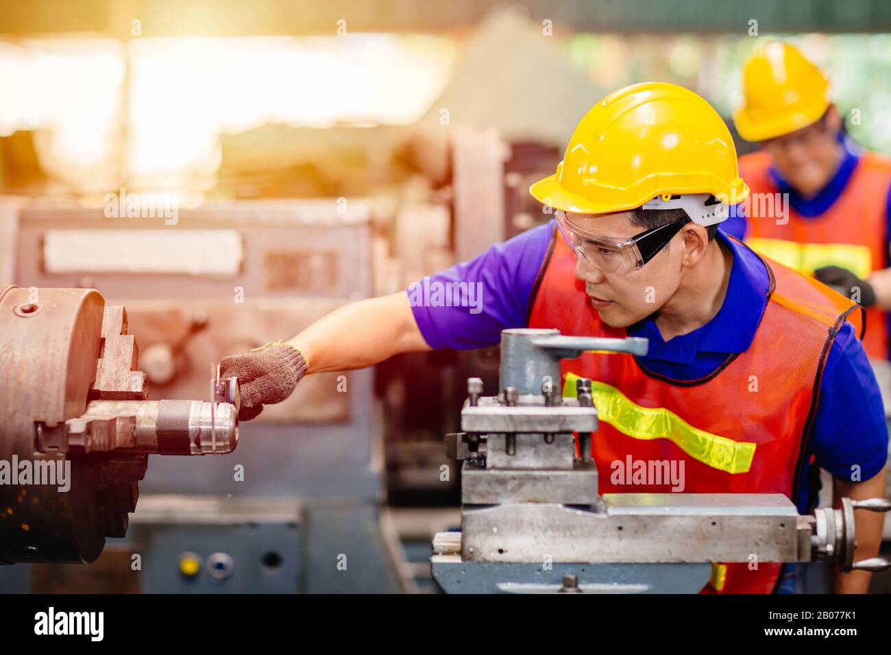 Asian engineer worker using Vernier Caliper to check size for accuracy precision quality control of service machine in factory. Stock Photo