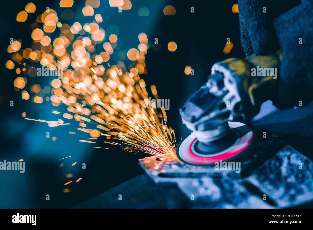 Closeup heavy steel worker using electric wheel grinding disc cuting metal plate in workplace danger fire light sparking from tool. Stock Photo