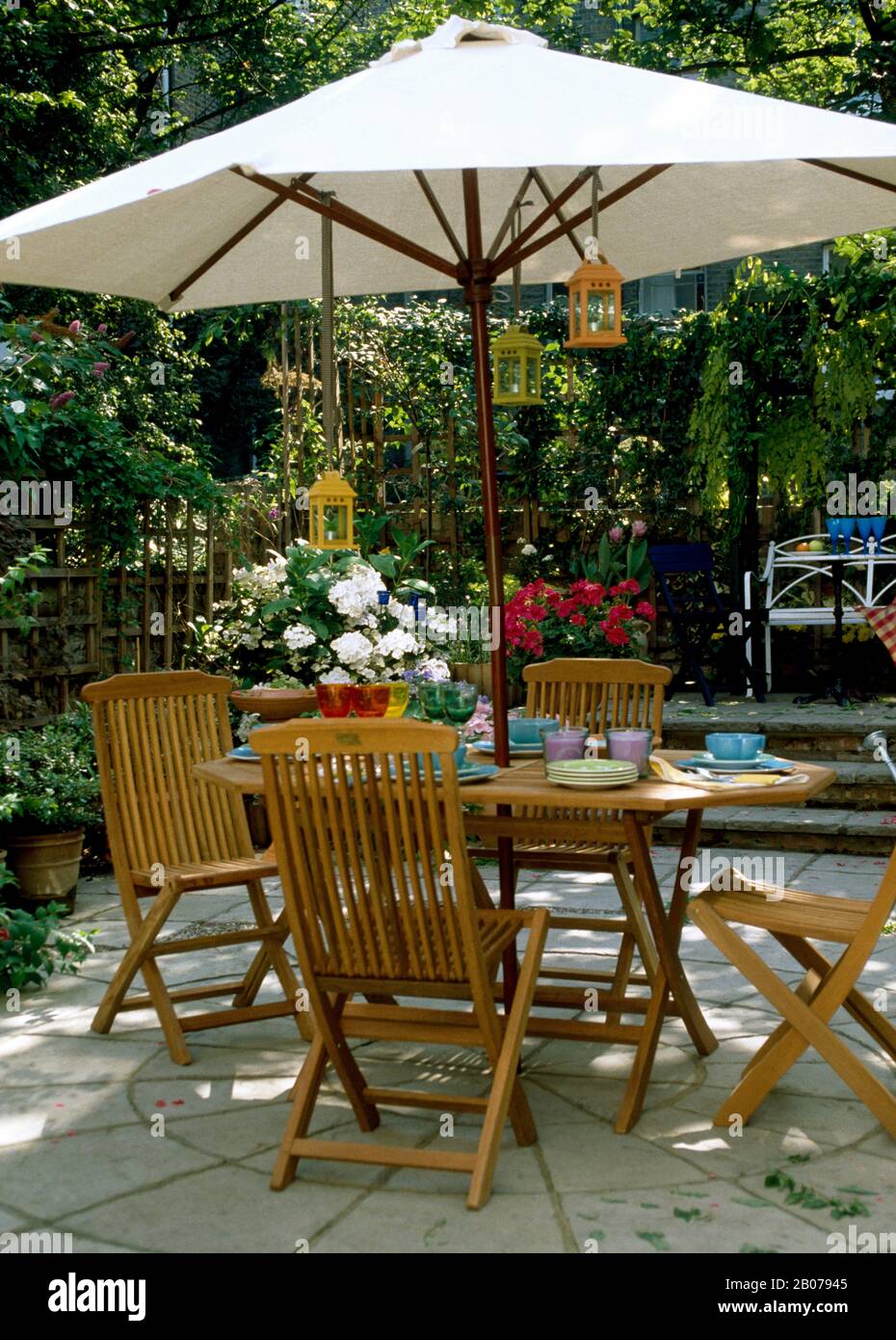Cream parasol over table and chairs in town garden Stock Photo ...