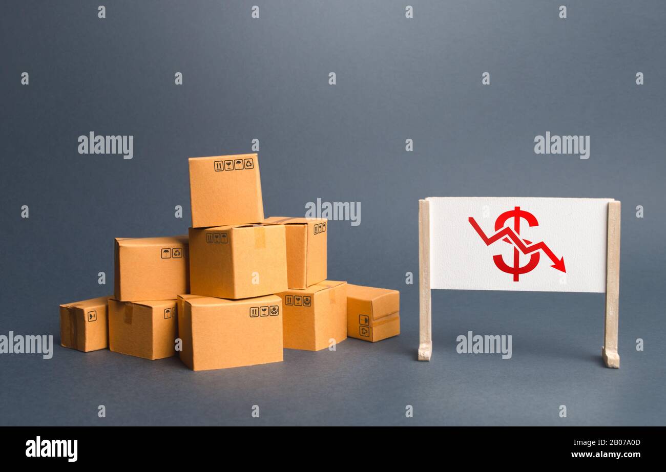 Pile of boxes and easel with red dollar arrow down chart. Drop profits, sales slowdown. Decrease in trade volumes, commodity prices. Unprofitable busi Stock Photo
