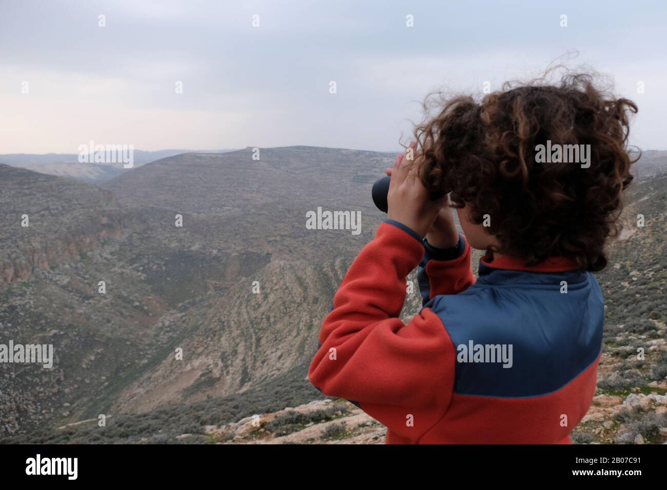 Young Jewish settler looking through binoculars at the canyon of Nahal Arugot river in Gush Etzion a cluster of Jewish settlements located in the Judaean Mountains in the West Bank Israel Stock Photo