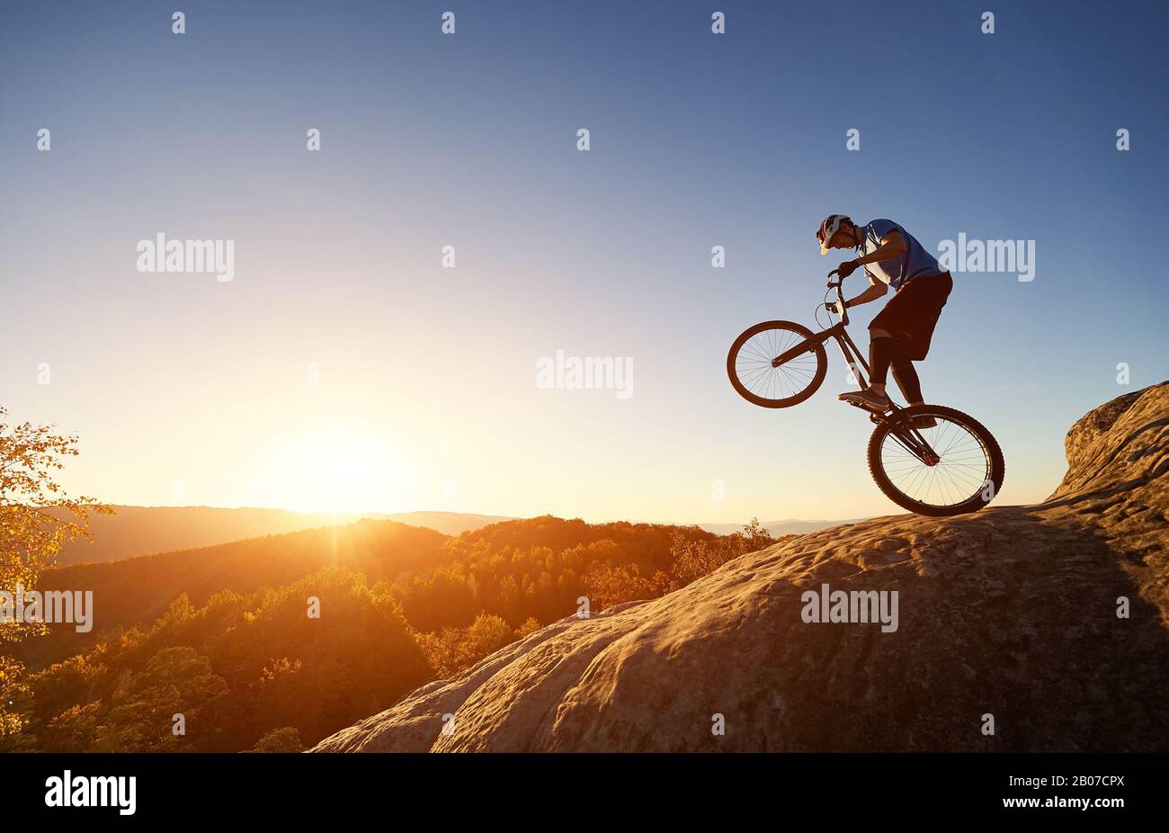 Silhouette of cyclist balancing on back wheel on trial bicycle