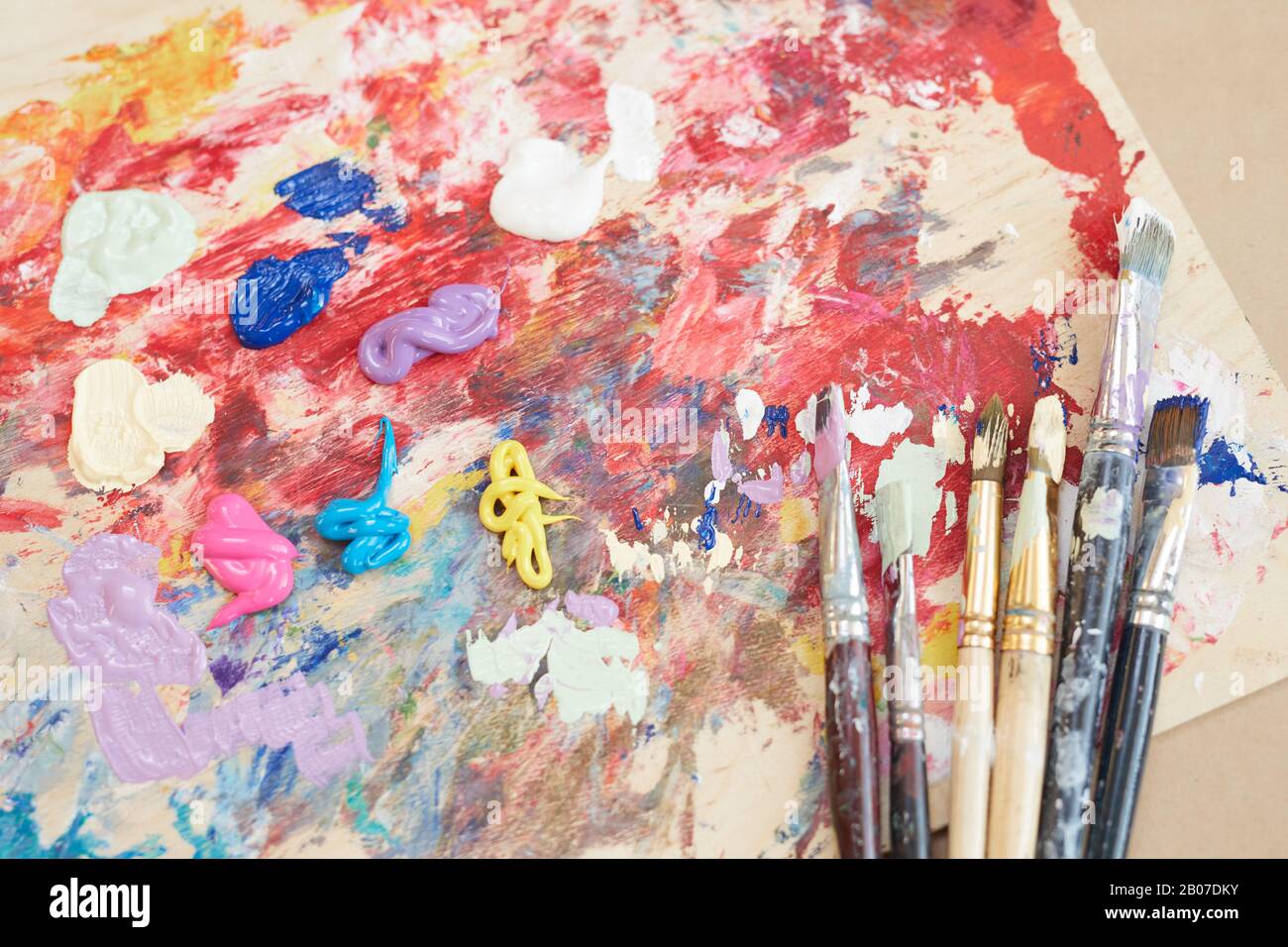 Close-up of palette with paints and different paintbrushes on the table in workshop Stock Photo