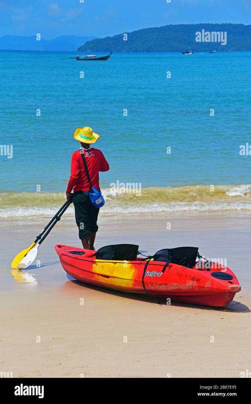 man standing next to a sea kayak on the Railay Beach, Thailand, Rai Leh, Krabi Stock Photo