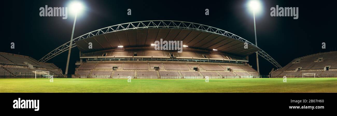 Huge empty football arena with lights. Large soccer stadium at night. Panoramic shot. Stock Photo