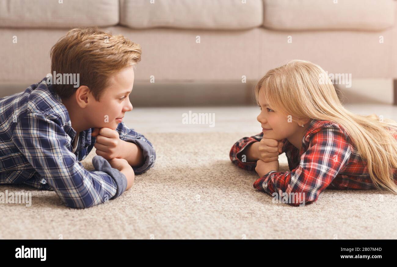 Siblings Trying To Stare Each Other Down Lying On Floor Stock Photo